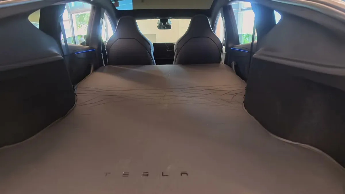 Tesla air mattress inflated flat across the folded cargo area of a Model Y Performance.