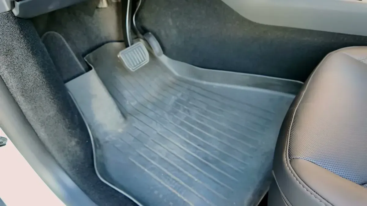 Black Tesla all-weather floor mat placed incorrectly in the Model Y Juniper driver's footwell, not fitting properly