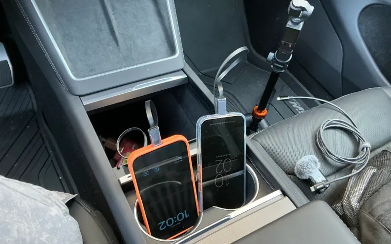 Two smartphones charging from the Hansshow GaN hub in a Tesla Model Y Juniper center console