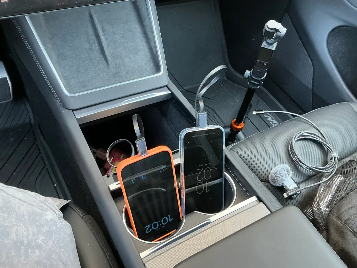 Two smartphones charging from the Hansshow GaN hub in a Tesla Model Y Juniper center console