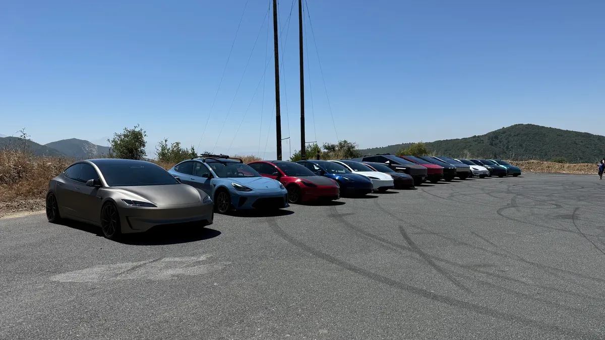 Tesla convoy including Model 3s, Model Ys, and a Cybertruck parked at a mountain road overlook in SoCal