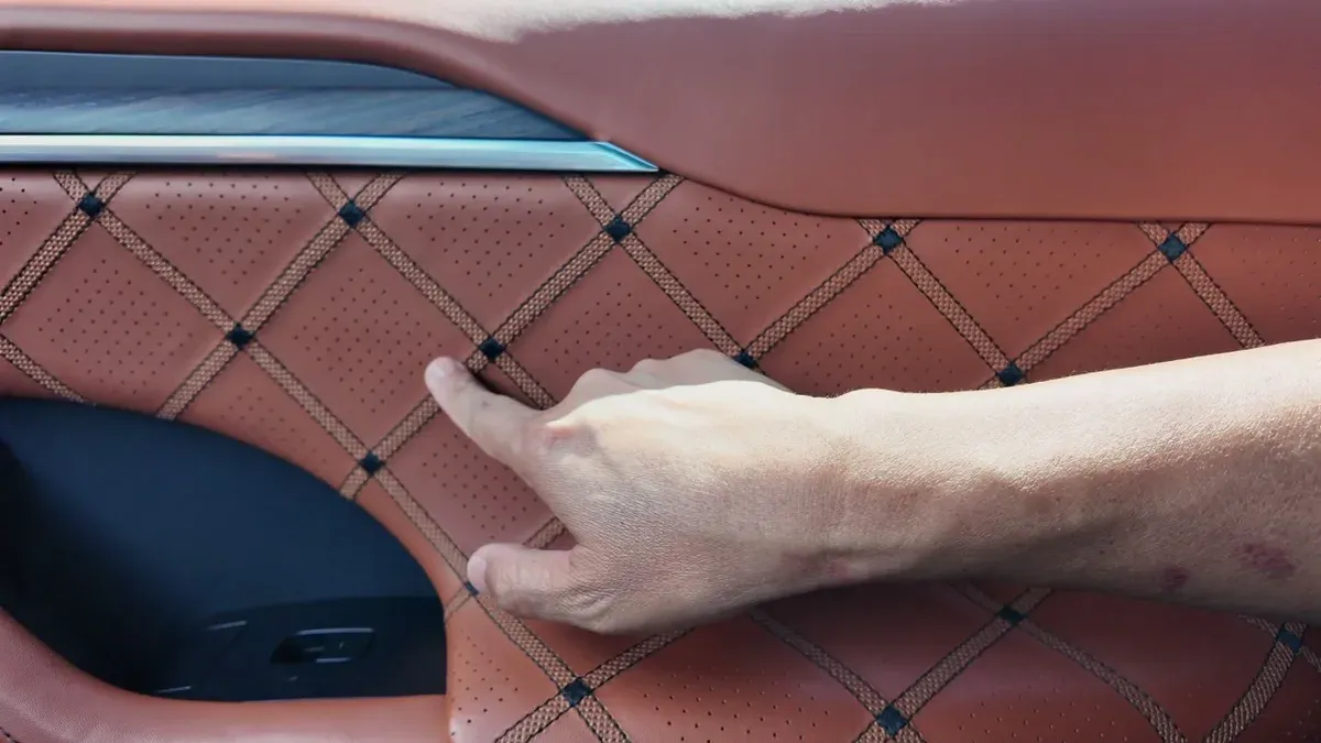 Close-up of hand touching quilted Nappa leather door panel in George's custom Model X