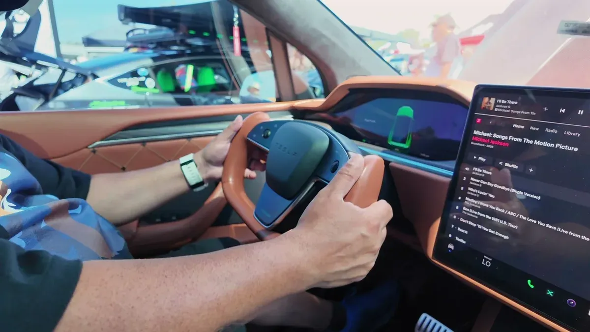 Custom Tesla yoke steering wheel wrapped in Nappa leather, infotainment screen visible