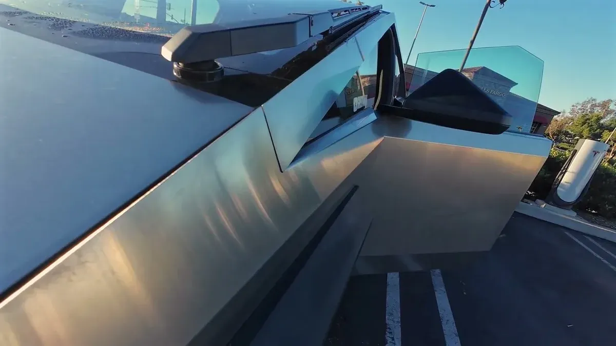 Close-up low-angle view of Tesla Cybertruck at Upland service center, Supercharger visible behind it