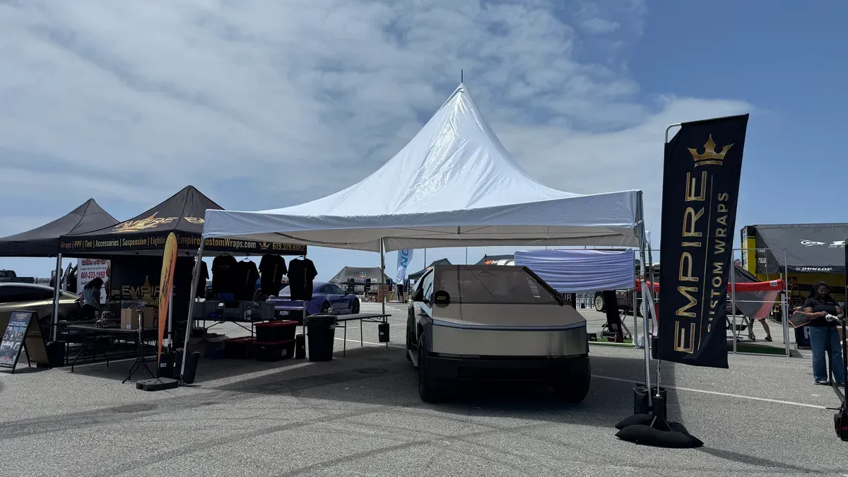 Tesla Cybertruck parked inside the Empire Custom Wraps tent at Electrify Expo with branded banners on both sides