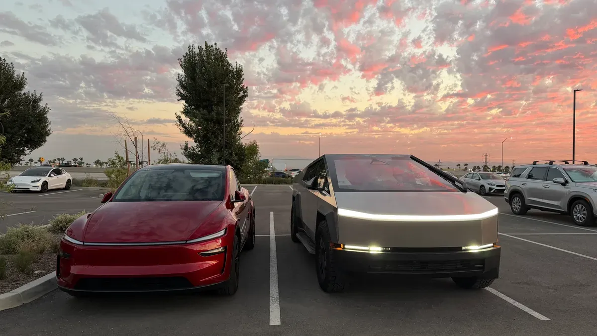 Tesla Cybertruck and red Lucid Air parked front-facing at sunset in the service center lot