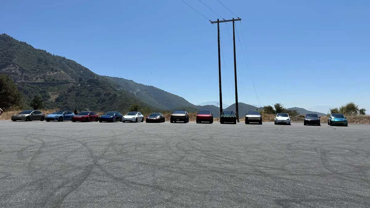 Wide shot of Tesla vehicles including Cybertrucks, Model 3s, and Model Ys lined up on a SoCal mountain road