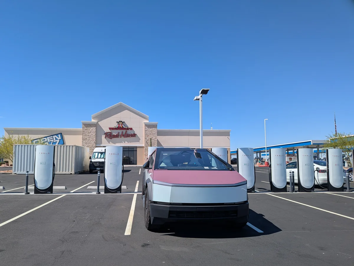 Cybertruck parked at a Supercharger in front of a Road House store