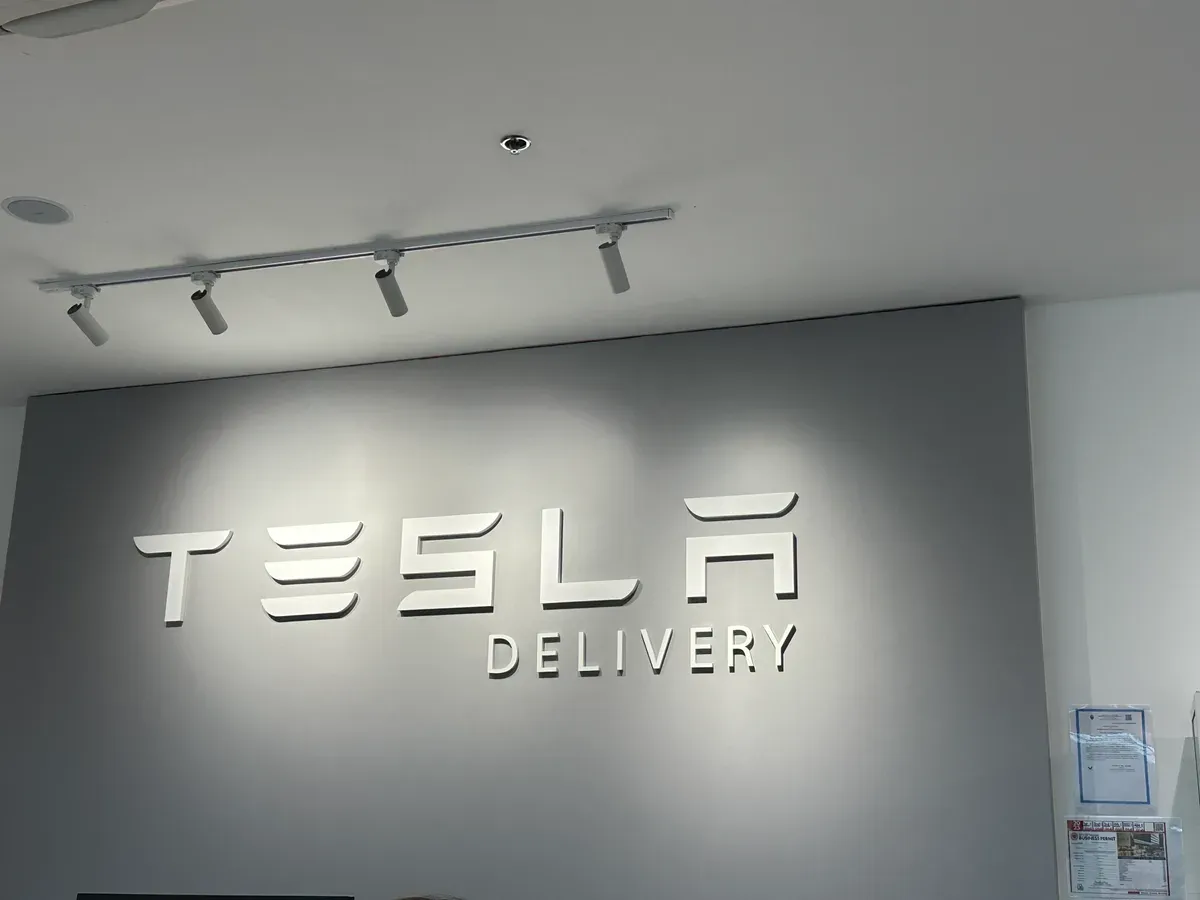 TESLA DELIVERY sign in white letters on the wall of the Tesla delivery center in BGC