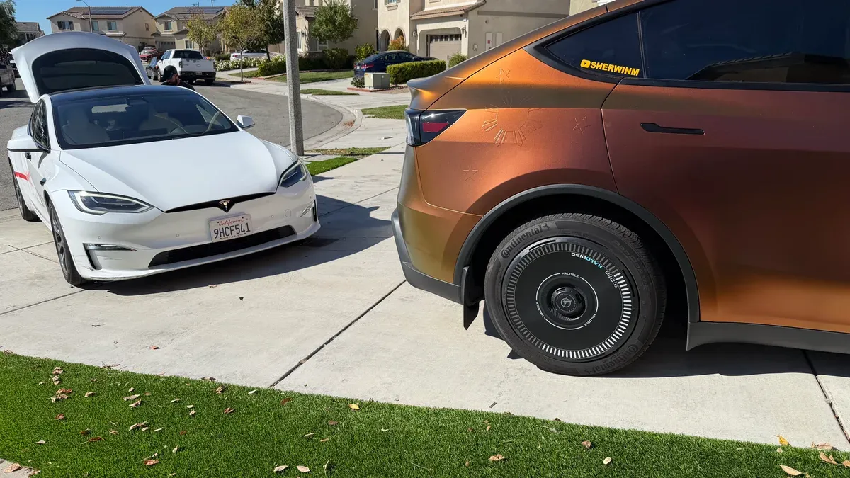 Bronze-wrapped Model Y Juniper with SHERWINM sticker parked next to a white Tesla Model S with frunk open
