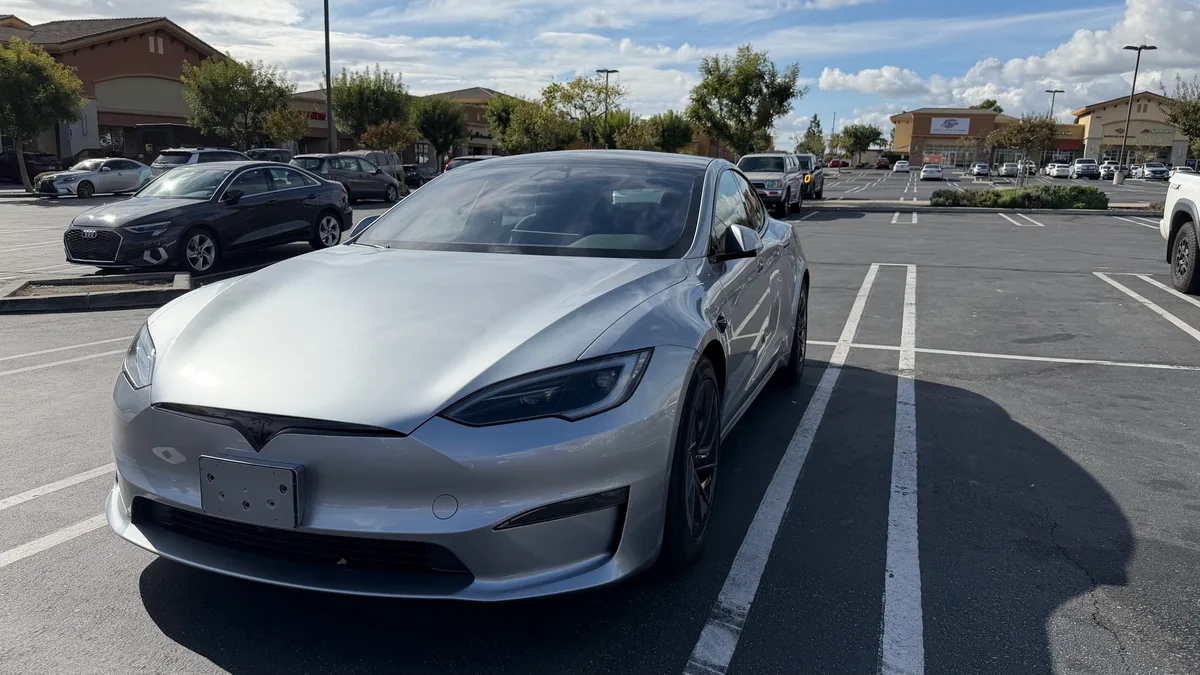 Silver 2026 Tesla Model S parked diagonally in a sunny SoCal shopping center parking lot.