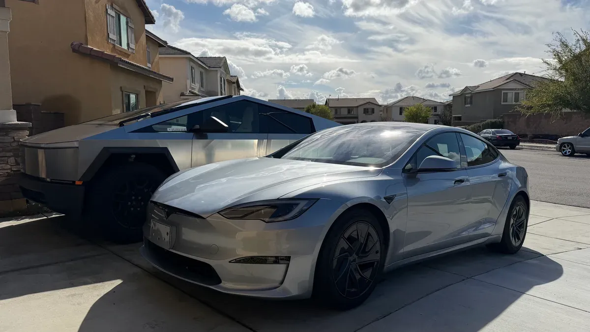 Silver 2026 Tesla Model S parked next to a Tesla Cybertruck in a residential driveway.