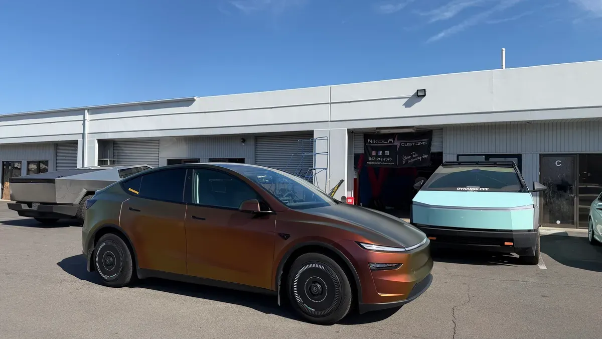 Model Y Juniper in Rising Sun wrap outside Nikola Customs, Cybertruck and another EV visible in background