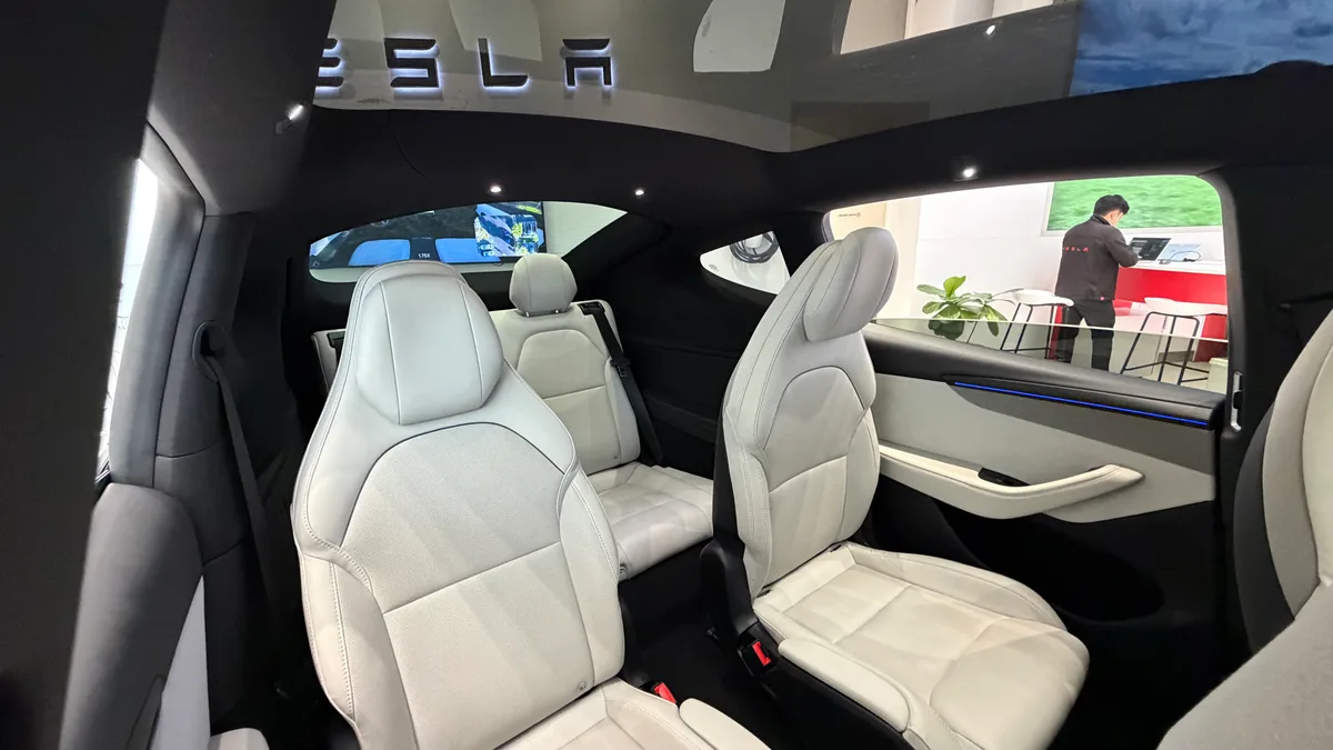 Wide view of the Tesla Model YL second row showing the panoramic roof and blue ambient lighting.