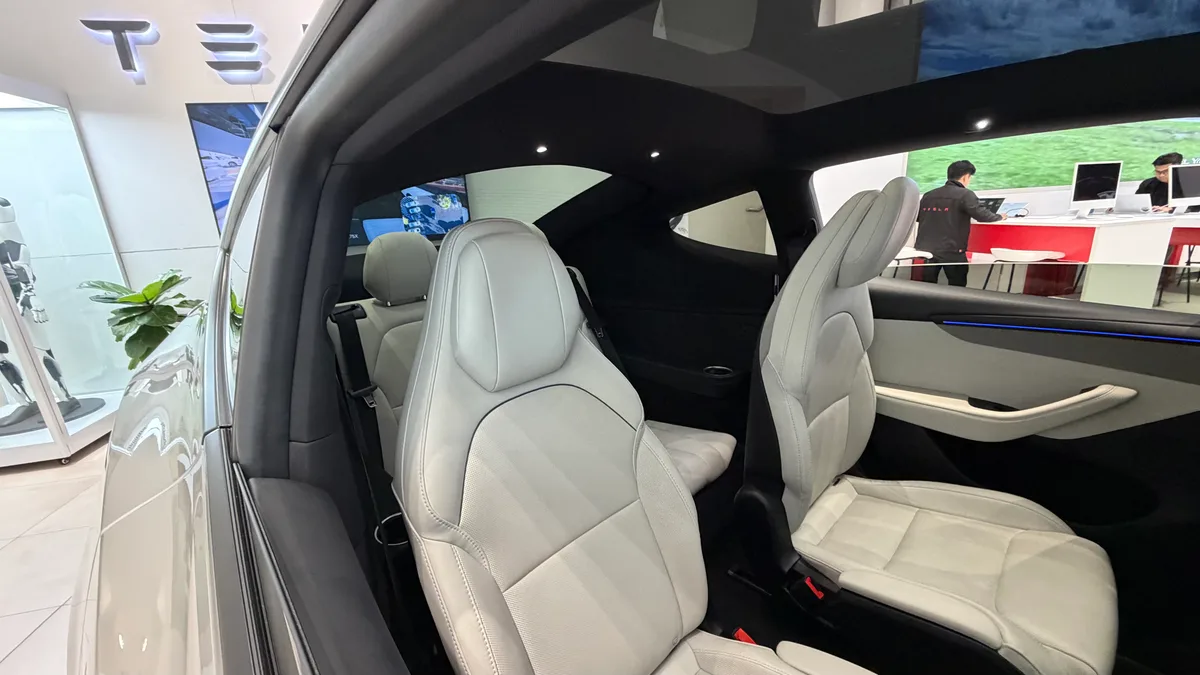 Second-row seats of the Tesla Model YL in light gray with the panoramic glass roof overhead.