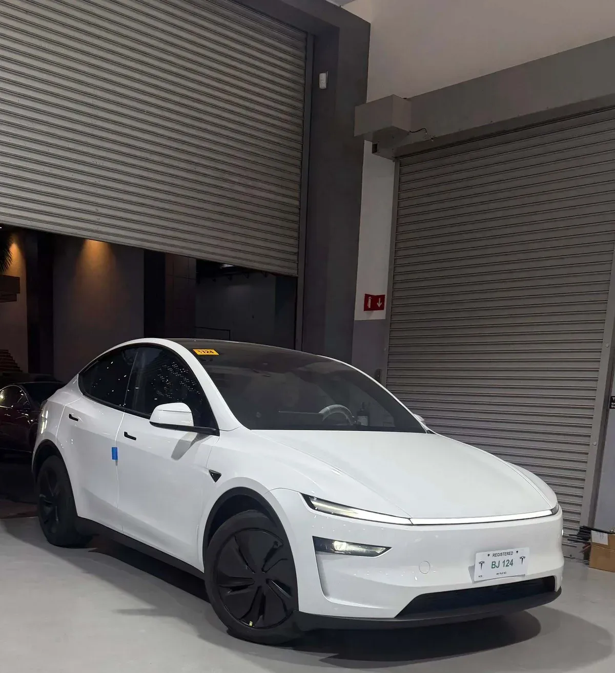 White Tesla Model Y Juniper in the Tesla delivery bay in the Philippines with its temporary registration plate