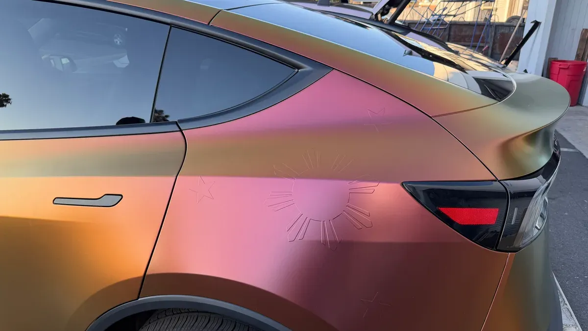 Close-up of the Philippine sun and stars embossed into the color-shifting wrap on the Model Y rear quarter panel