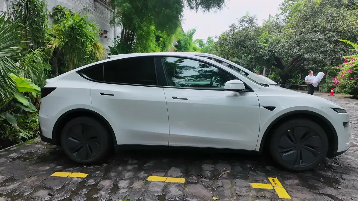 Side profile of Joy's white Tesla Model Y Premium RWD parked on a cobblestone driveway in the Philippines