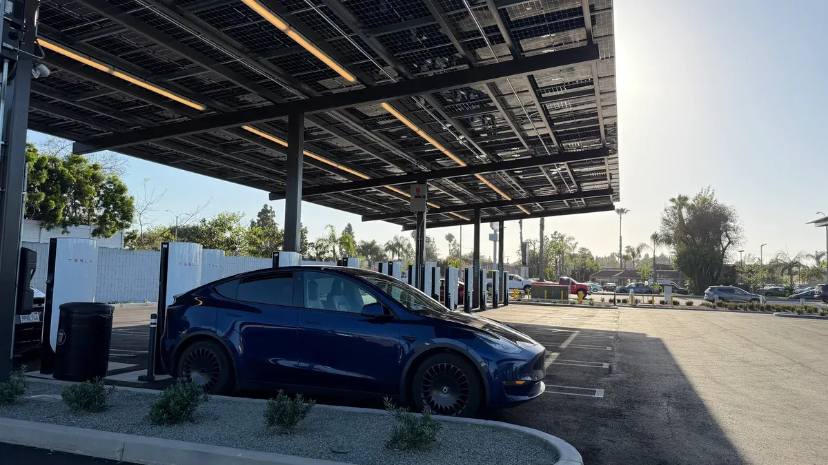 Tesla Model Y at a Tesla Supercharger station under a large solar canopy at Rove Costa Mesa.