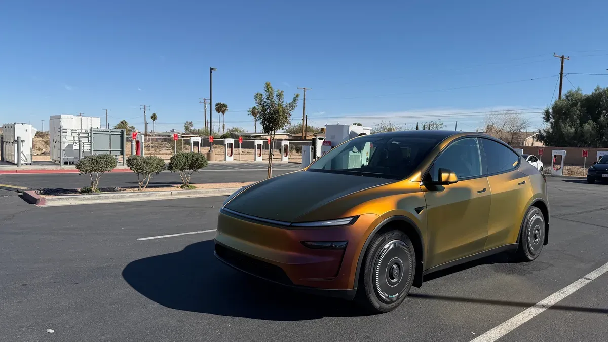 Color-shifting Model Y Juniper in Avery Dennison Rising Sun wrap at a Supercharger station