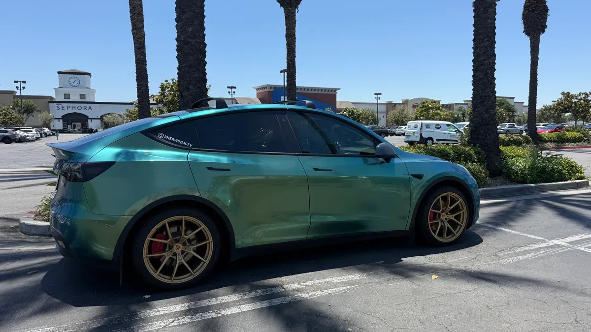 Sherwin's previous Tesla Model Y with teal color-shift wrap, gold wheels, and red calipers