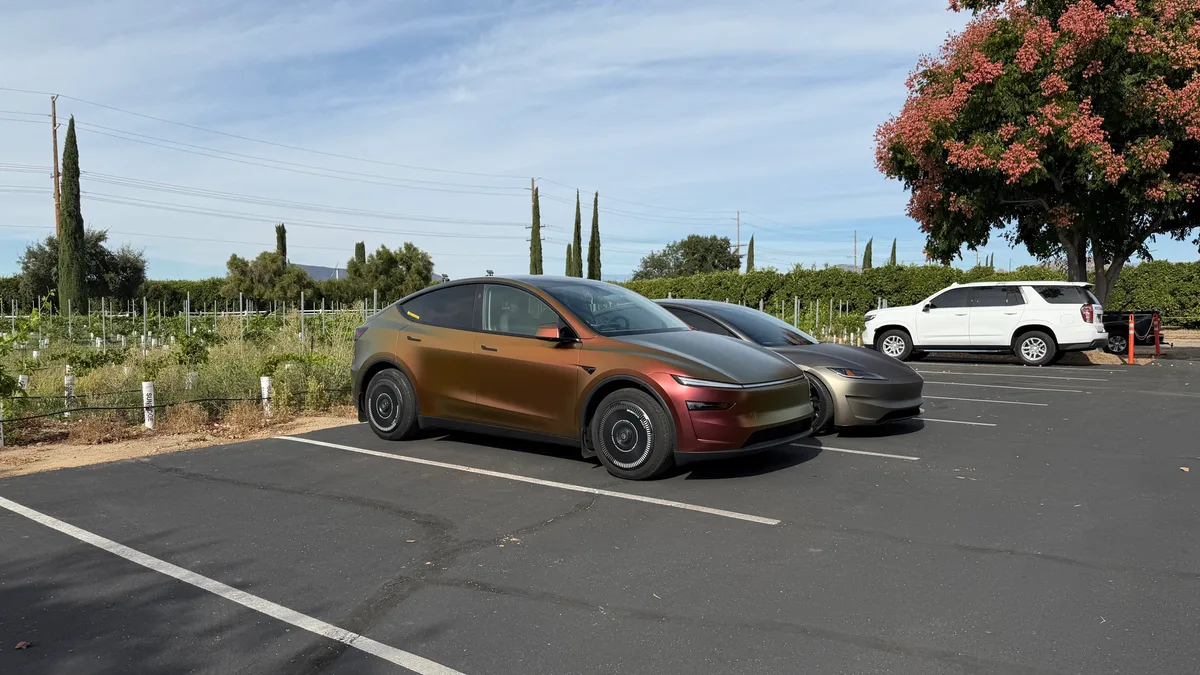 Model Y Juniper in Rising Sun wrap from the front at a vineyard parking lot, showing gold-to-rose color shift