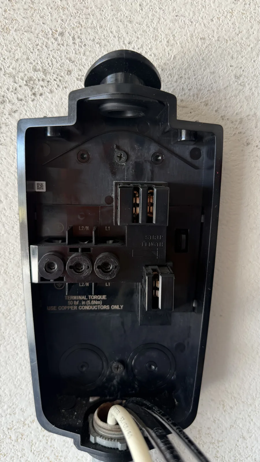 Tesla Wall Connector opened up on the wall showing the L1, L2 and ground terminals