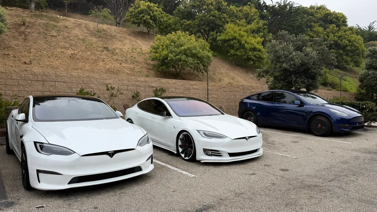 Three Tesla Model S sedans parked on a hillside pullout along Pacific Coast Highway