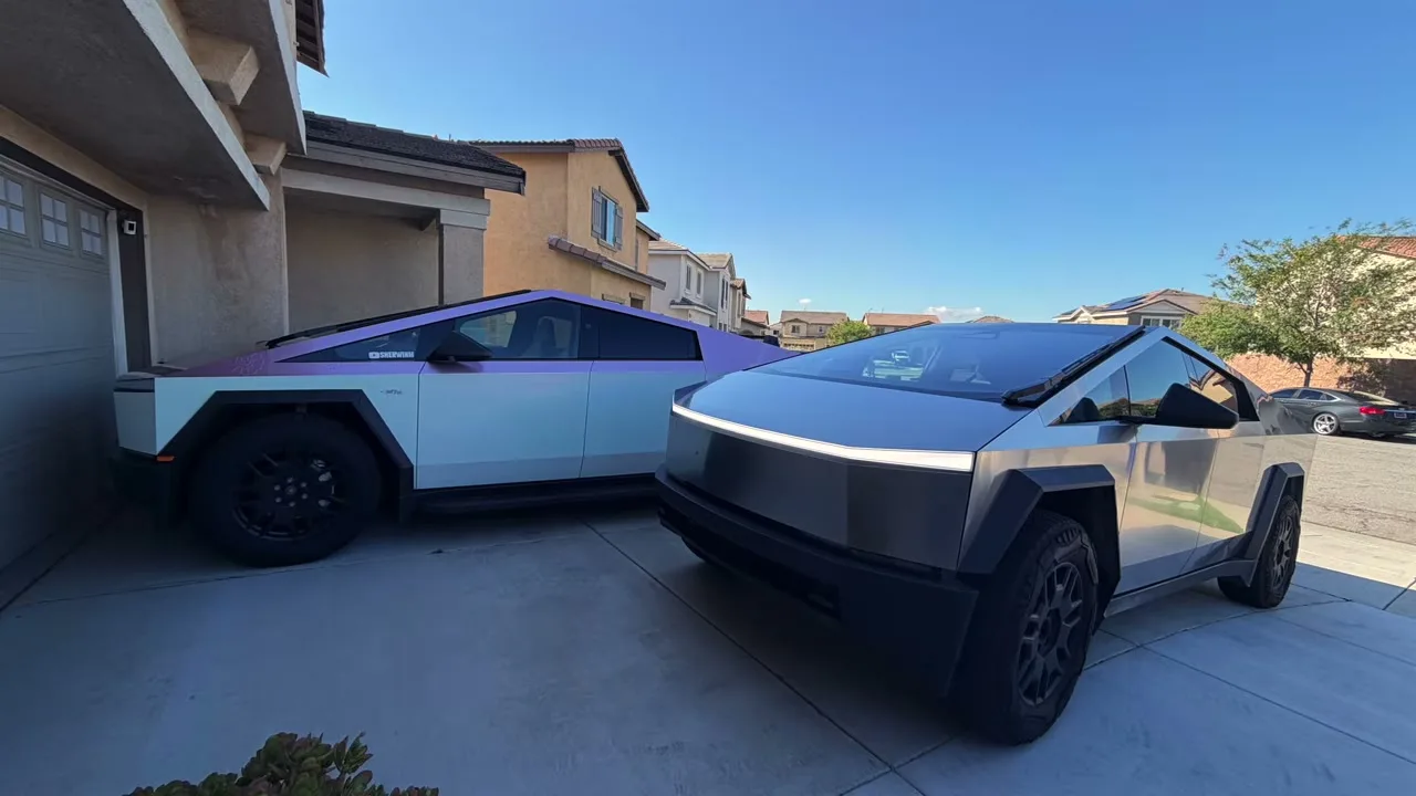 Two Tesla Cybertrucks parked side by side in a driveway, one wrapped and one stainless steel loaner