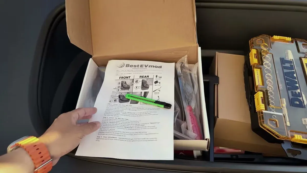 Hands unboxing BestEVMod mud flaps with instructions and tools next to a DeWalt case.