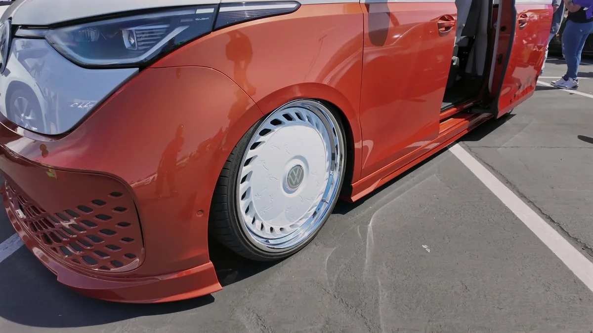 Extreme low-angle of the custom orange VW ID. Buzz front wheel and fender showing the lowered stance