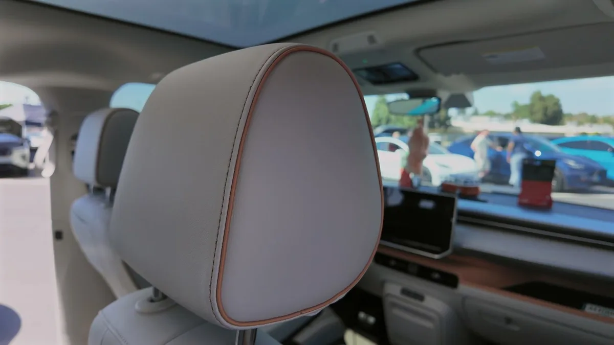 Close-up of a light grey headrest with orange stitching inside the VW ID. Buzz