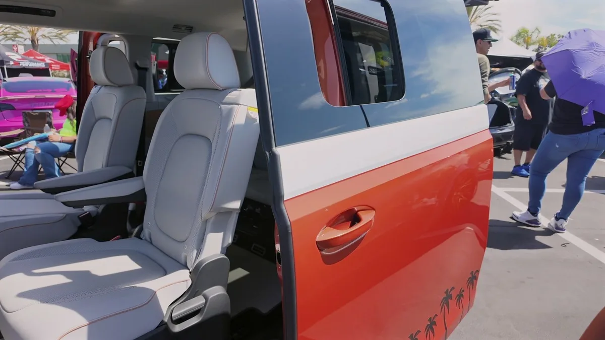 Interior of the VW ID. Buzz with grey seats and orange piping seen through the open sliding door