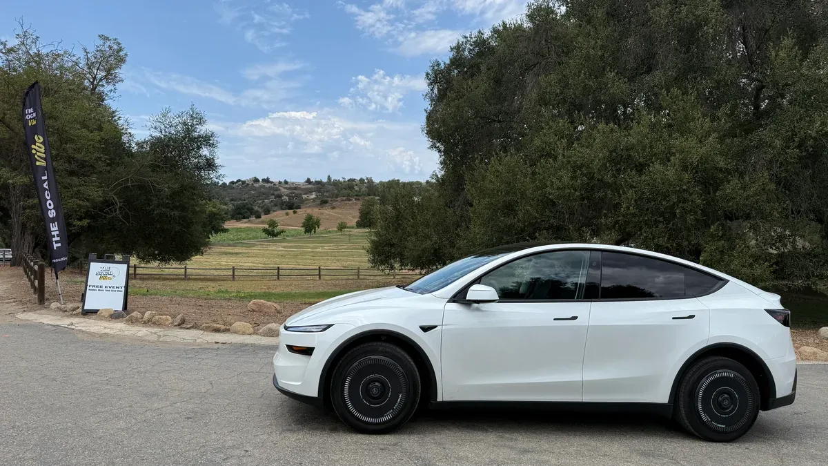 White Alpha Motor Corporation ACE Coupe parked near the SoCal Vibe banner at the event entrance