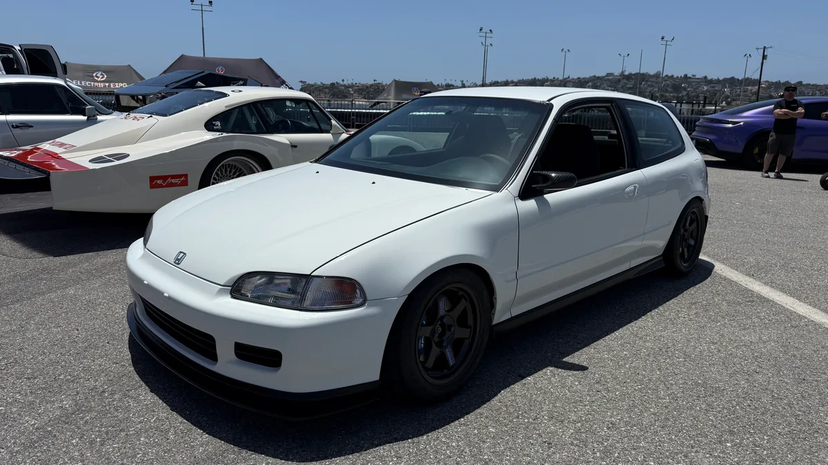 Clean white Honda Civic EG hatchback with aftermarket wheels parked at Electrify Expo