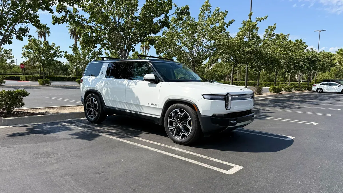 White Rivian R1S with cargo crossbars installed, parked in a sunny lot