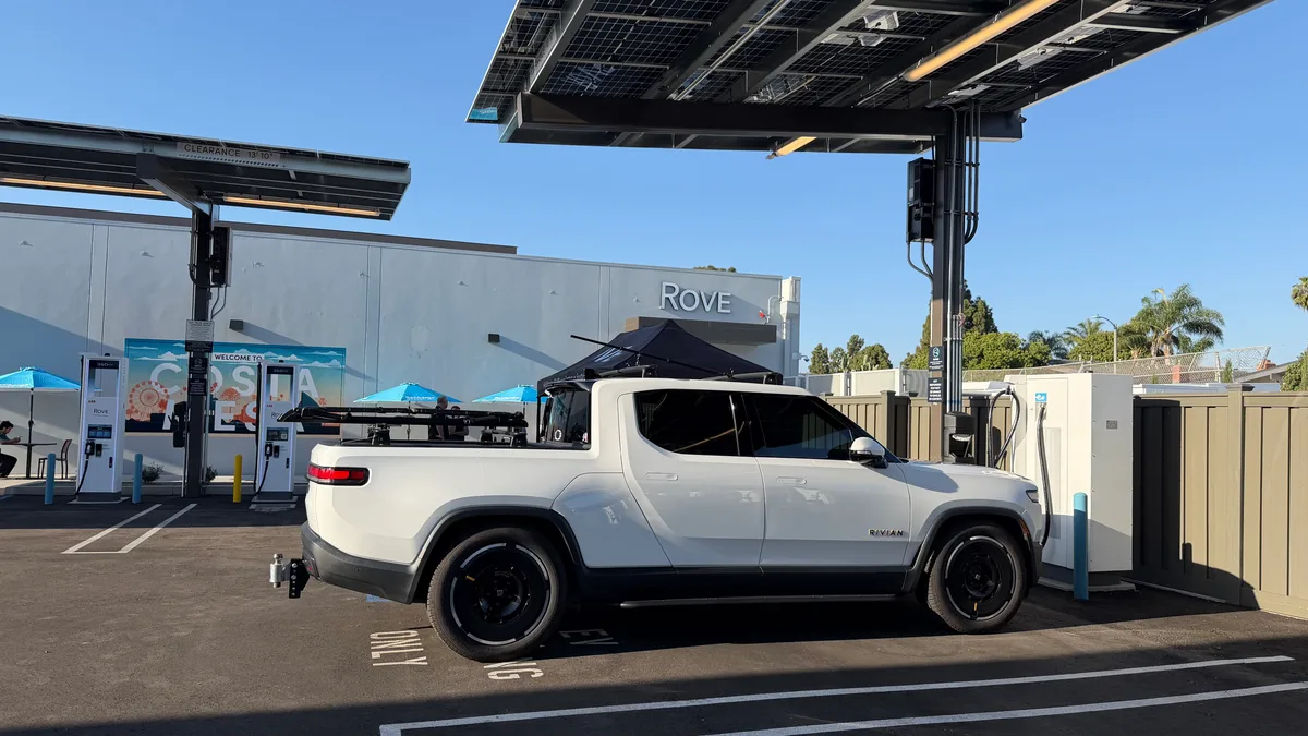 White Rivian R1T pickup truck charging at Rove EV station with solar canopy overhead.