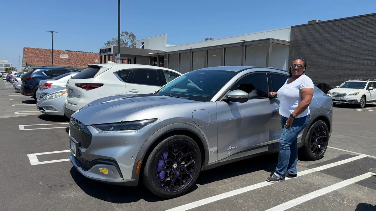 Keisha standing next to her silver Ford Mustang Mach-E with custom purple wheels at Rove