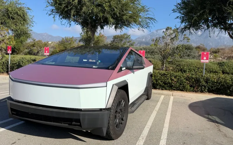 Two-tone white and plum wrapped Tesla Cybertruck parked at Tesla Service Upland with the San Gabriel Mountains behind it.