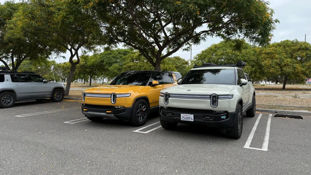 Compass Yellow and California Dune Rivian R1S SUVs parked side by side